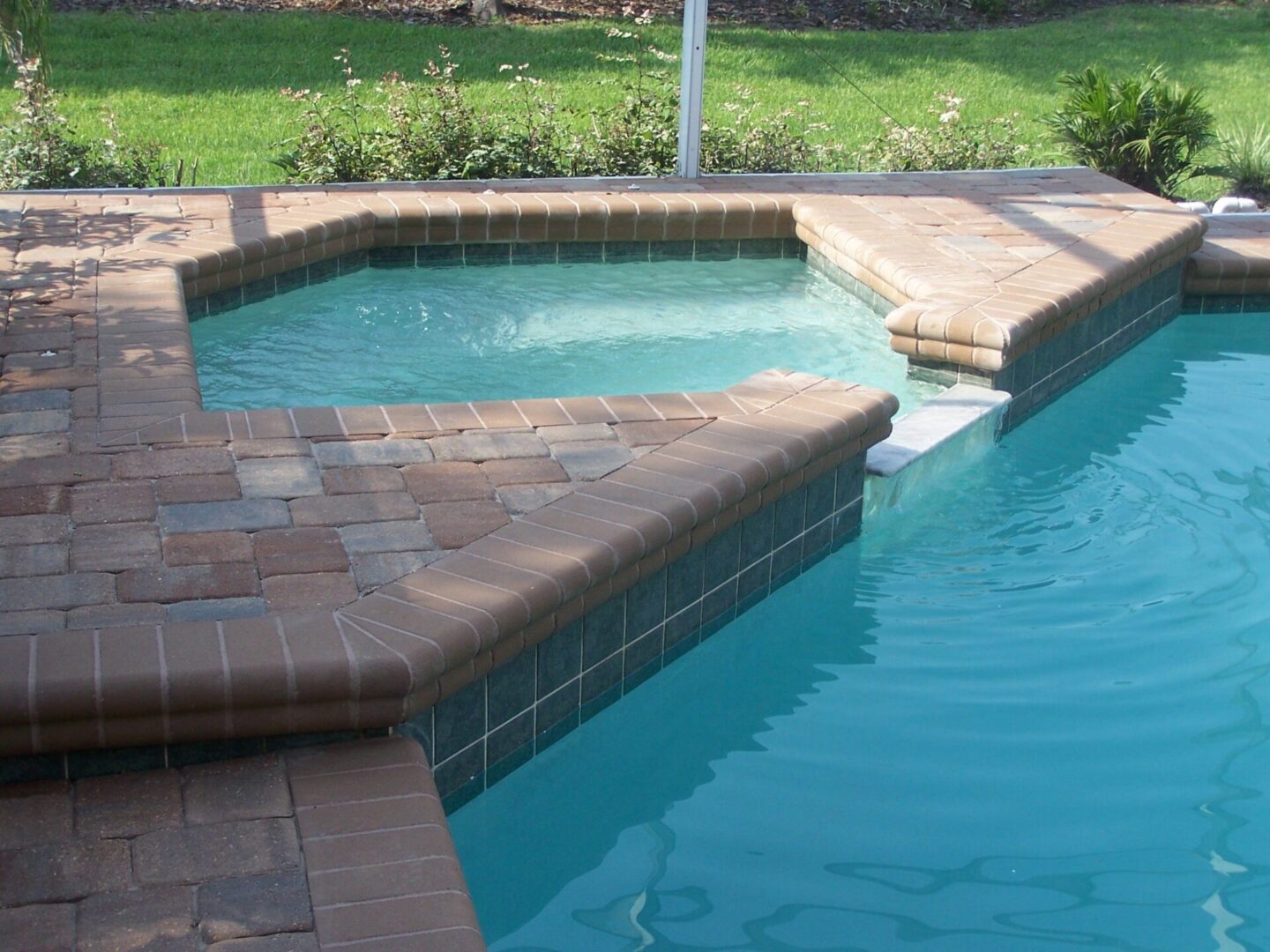 Tan brick pavers pool deck next to hot tub and pool